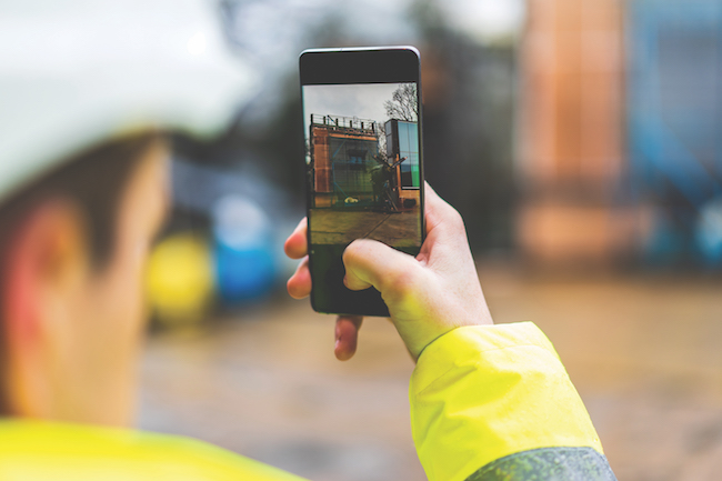 Construction worker using phone to record site progress